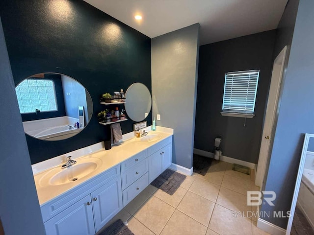 bathroom with double vanity, a bathtub, tile patterned floors, and baseboards