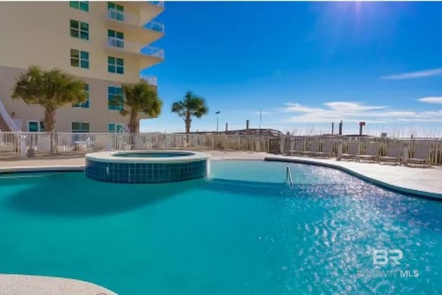 view of swimming pool with a pool with connected hot tub and fence