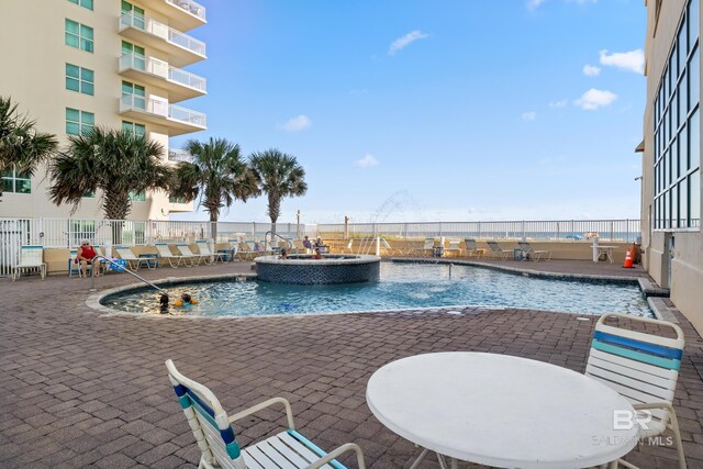 view of pool featuring a patio area, fence, and a pool with connected hot tub