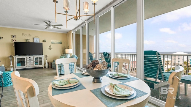 1524 W Beach Blvd Unit 603, Gulf Shores, AL 36542 - dining space with a chandelier, a wall of windows, wood finished floors, ceiling fan, and crown molding