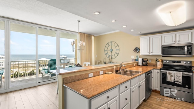 1524 W Beach Blvd Unit 603, Gulf Shores, AL 36542 - kitchen with stainless steel appliances, a sink, a peninsula, light wood-style floors, and a water view