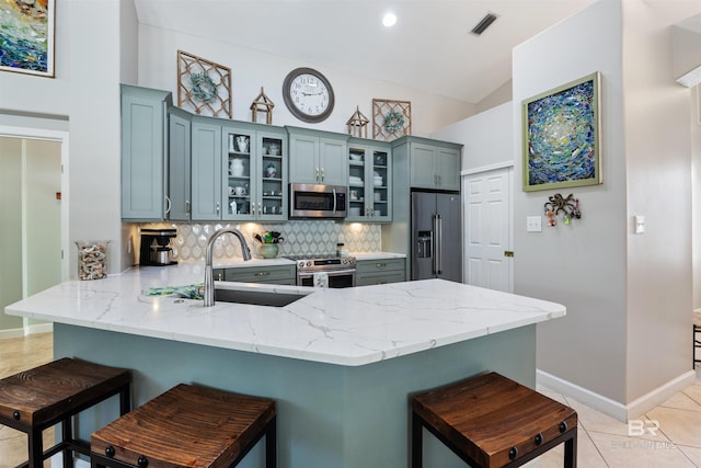 kitchen featuring kitchen peninsula, a kitchen breakfast bar, tasteful backsplash, stainless steel appliances, and lofted ceiling