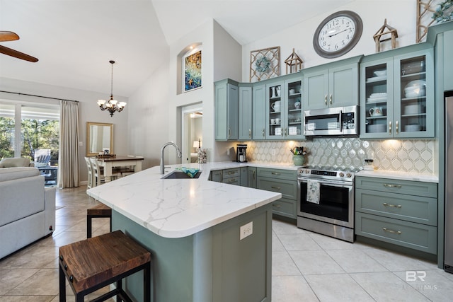 kitchen with sink, appliances with stainless steel finishes, tasteful backsplash, decorative light fixtures, and kitchen peninsula