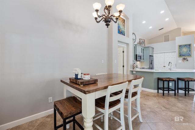 dining space featuring sink, light tile patterned flooring, high vaulted ceiling, and an inviting chandelier