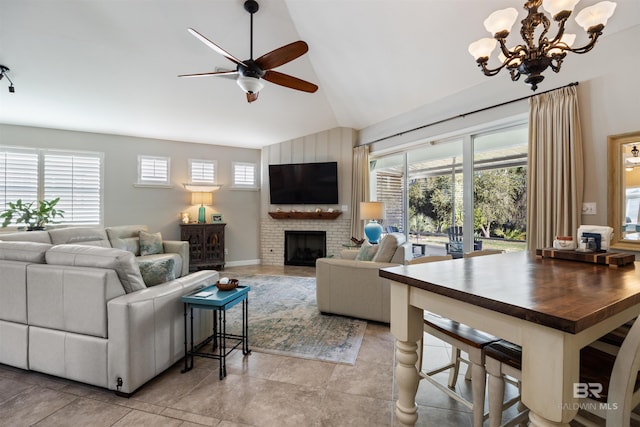 tiled living room featuring ceiling fan with notable chandelier, vaulted ceiling, and a brick fireplace