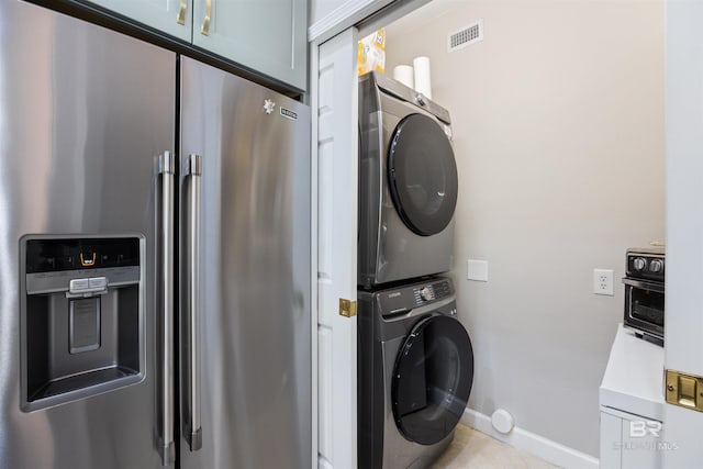 washroom with light tile patterned flooring and stacked washing maching and dryer