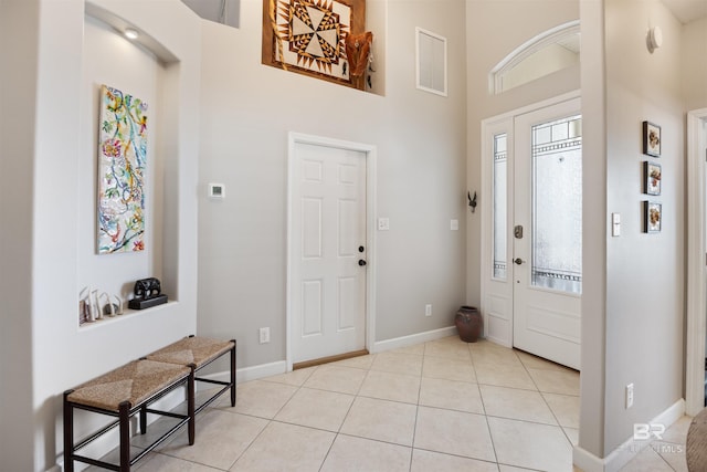 tiled entrance foyer featuring a wealth of natural light and a towering ceiling