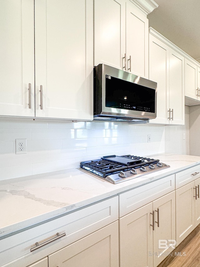23850 Shadowridge Dr, Daphne, AL 36526 - kitchen featuring appliances with stainless steel finishes, white cabinets, decorative backsplash, light stone counters, and light wood-style flooring