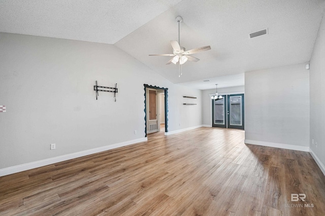 unfurnished living room featuring hardwood / wood-style floors, ceiling fan with notable chandelier, vaulted ceiling, and a textured ceiling