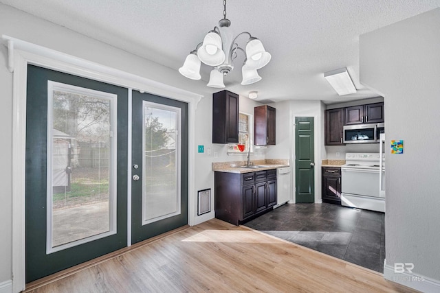 kitchen featuring dark brown cabinetry, sink, hanging light fixtures, white appliances, and light hardwood / wood-style floors