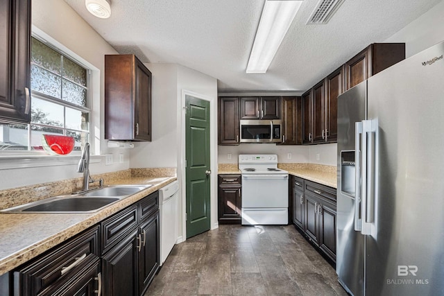 kitchen with dark brown cabinetry, sink, stainless steel appliances, and a textured ceiling