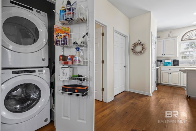 washroom with stacked washing maching and dryer, baseboards, laundry area, and dark wood-type flooring