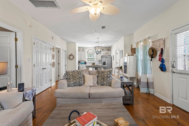 living room featuring visible vents, dark wood-type flooring, and a wealth of natural light