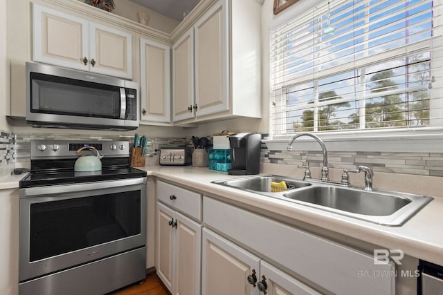 kitchen featuring a sink, stainless steel appliances, light countertops, and white cabinets