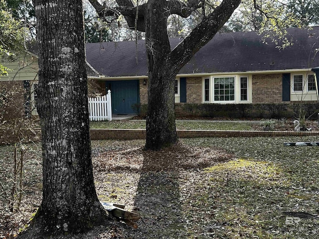 view of front facade with brick siding and fence