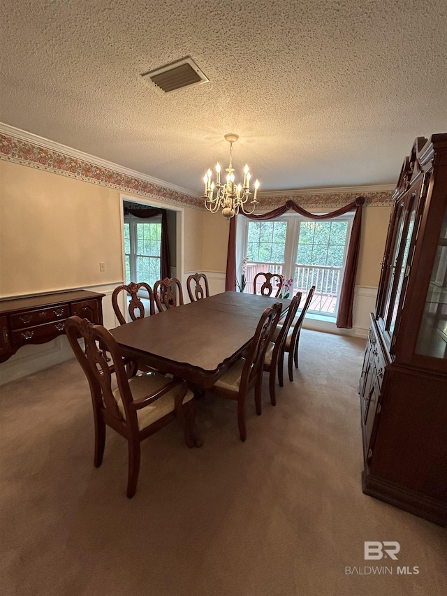 dining space with a chandelier, visible vents, light colored carpet, and crown molding