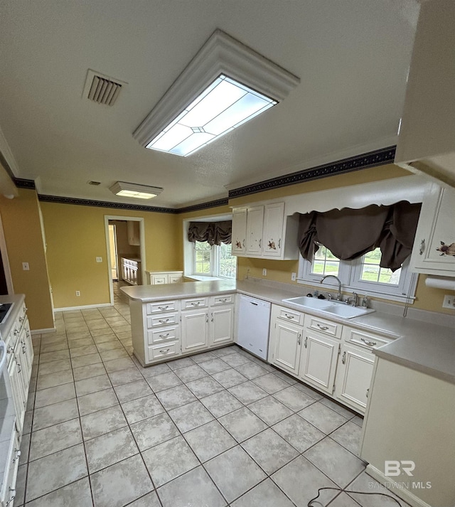 kitchen with visible vents, a peninsula, white dishwasher, a sink, and crown molding