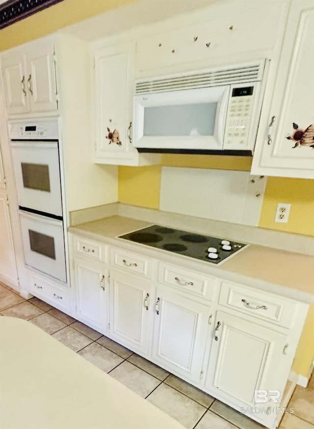 kitchen featuring light tile patterned floors, white appliances, white cabinetry, and light countertops