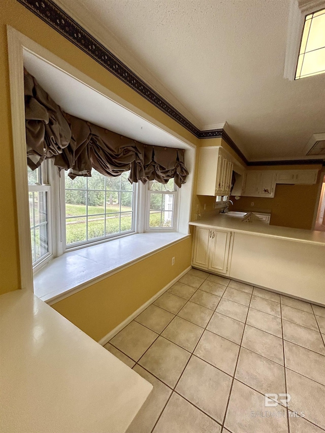 kitchen featuring light tile patterned floors, a sink, light countertops, a textured ceiling, and crown molding