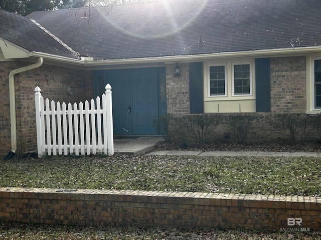 doorway to property featuring brick siding and fence