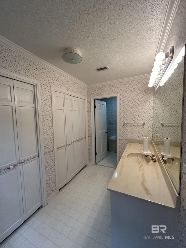 bathroom with wallpapered walls, crown molding, and a textured ceiling