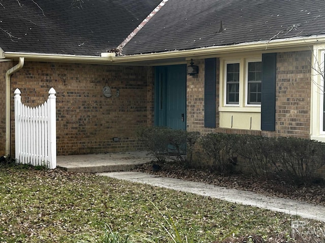 entrance to property with brick siding and roof with shingles