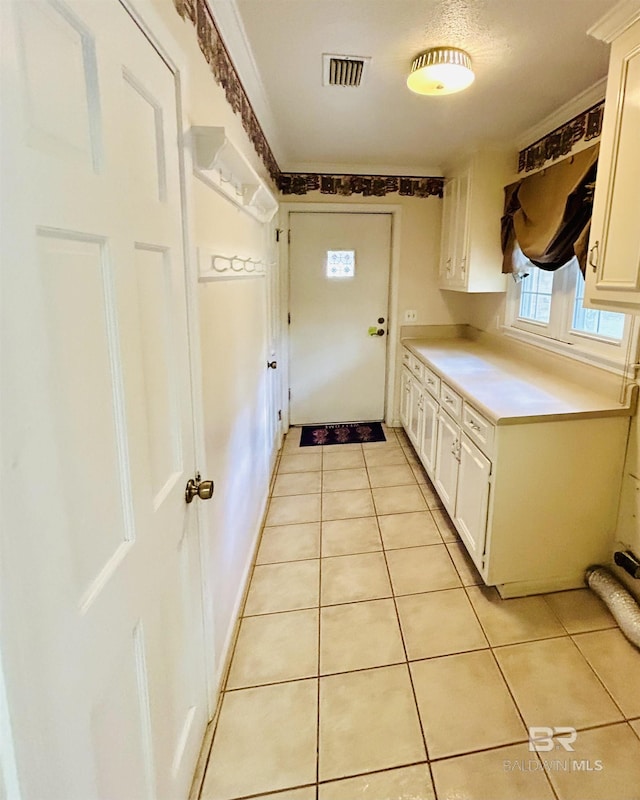 interior space with light countertops, white cabinets, light tile patterned floors, and visible vents