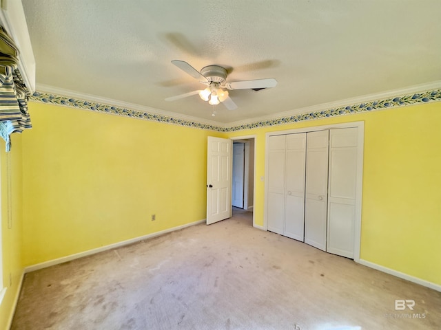 unfurnished bedroom with ceiling fan, baseboards, light colored carpet, ornamental molding, and a textured ceiling