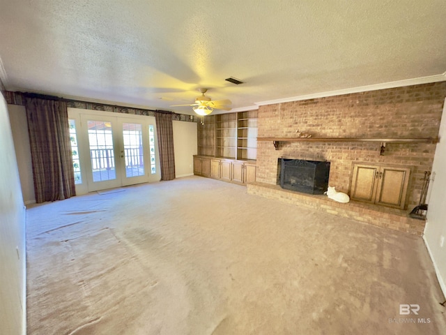 unfurnished living room with built in shelves, light colored carpet, french doors, a fireplace, and a textured ceiling