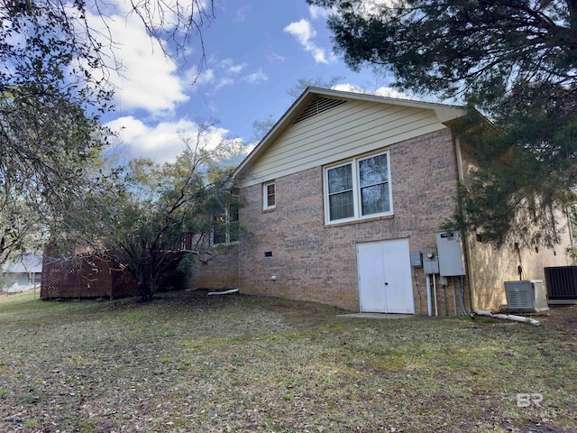 rear view of property with a yard, central AC unit, and brick siding