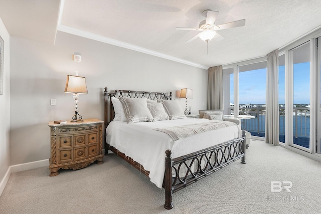 carpeted bedroom with ornamental molding, floor to ceiling windows, a water view, and access to exterior