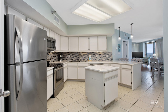 kitchen featuring tasteful backsplash, white cabinets, stainless steel appliances, and a kitchen island