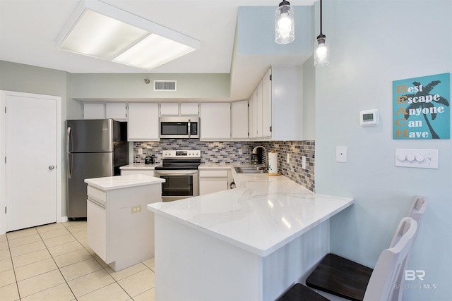 kitchen featuring stainless steel appliances, a center island, decorative light fixtures, white cabinets, and sink