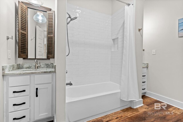 full bathroom with baseboards, wood finished floors, vanity, and shower / bathtub combination with curtain