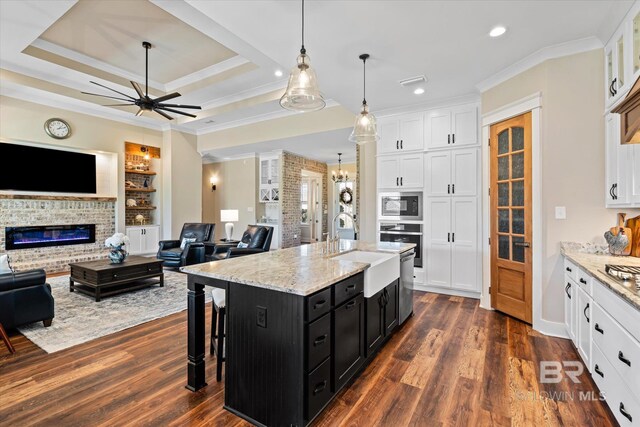 kitchen with a sink, open floor plan, dark cabinetry, and oven
