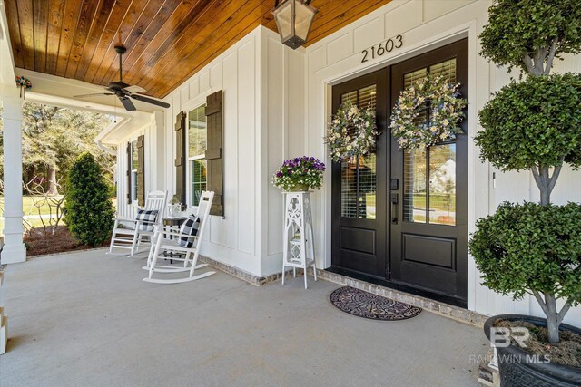 view of exterior entry featuring french doors, board and batten siding, a porch, and a ceiling fan