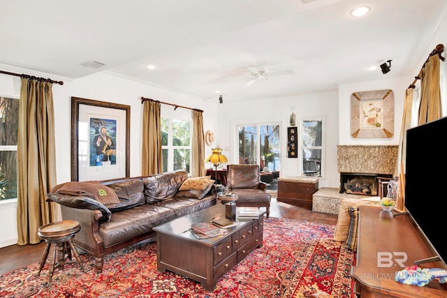 living room with visible vents, a fireplace with raised hearth, ceiling fan, dark wood finished floors, and recessed lighting