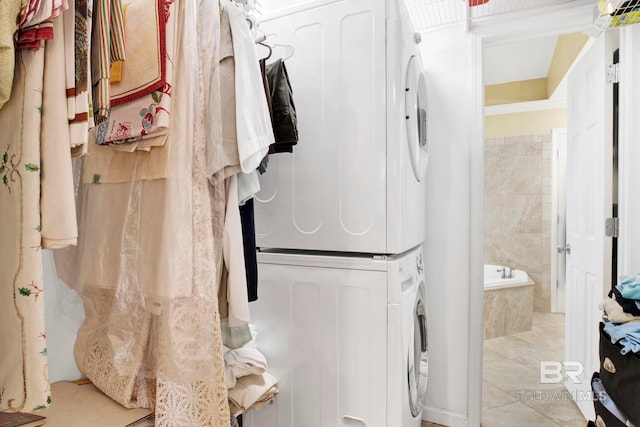 bathroom featuring tiled tub and stacked washer and clothes dryer