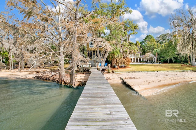 view of dock with a yard and a water view