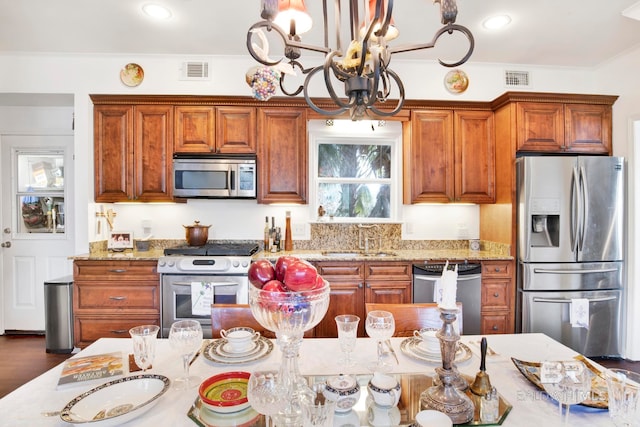 kitchen with a sink, light stone counters, visible vents, and stainless steel appliances