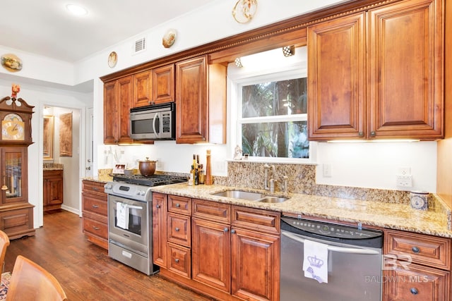 kitchen with visible vents, a sink, dark wood finished floors, appliances with stainless steel finishes, and brown cabinetry