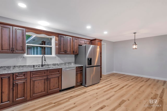 kitchen featuring appliances with stainless steel finishes, light hardwood / wood-style floors, sink, and light stone counters