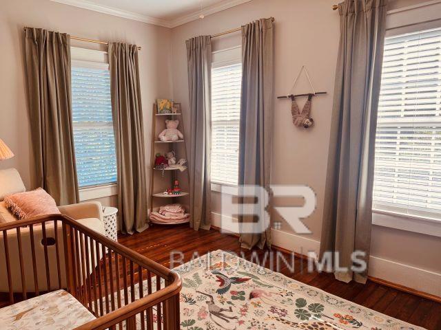 54 S Catherine St, Mobile, AL 36604 - bedroom with baseboards, wood finished floors, ornamental molding, and a nursery area
