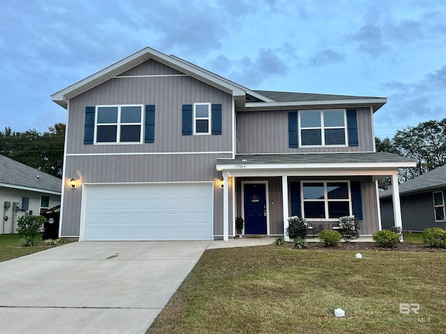 view of front of home featuring covered porch, a garage, and a front yard