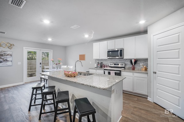 kitchen with sink, dark wood-type flooring, a center island with sink, white cabinets, and appliances with stainless steel finishes