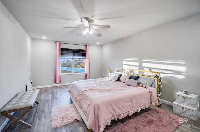 bedroom featuring dark hardwood / wood-style floors, ceiling fan, and multiple windows