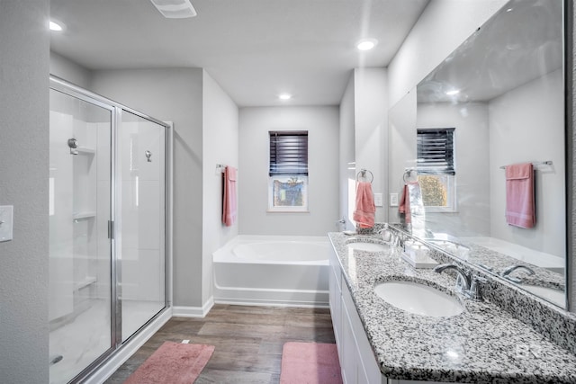 bathroom with hardwood / wood-style flooring, vanity, and plus walk in shower