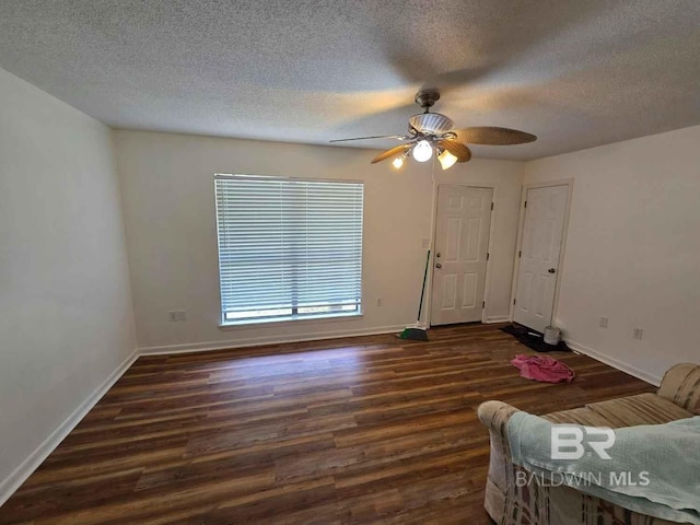 living room featuring wood finished floors, baseboards, and a textured ceiling