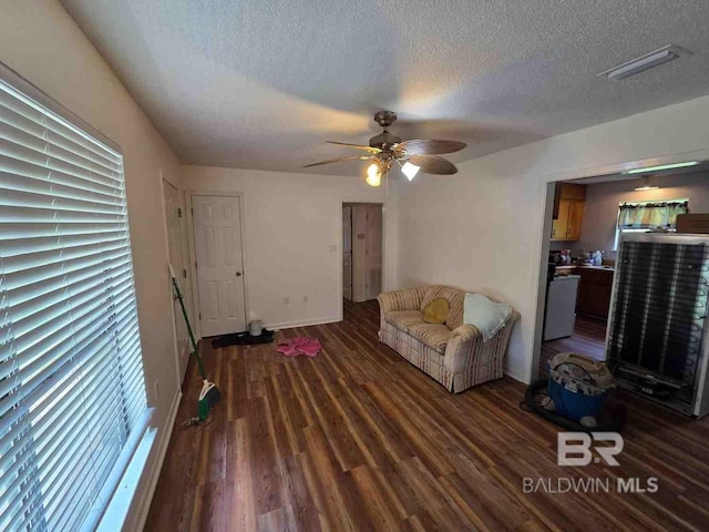 living room with a textured ceiling, wood finished floors, ceiling fan, and baseboards