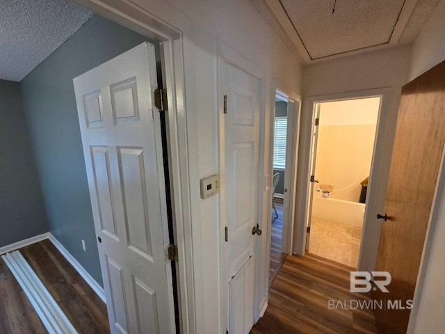 corridor with dark wood-type flooring and baseboards